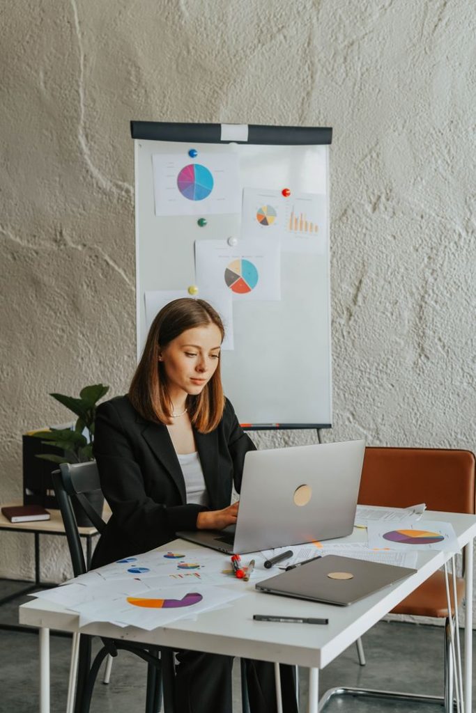 The Art of Drawing Readers In: Your attractive post title goes here Professional woman in blazer analyzing charts and graphs on laptop in modern office setting.